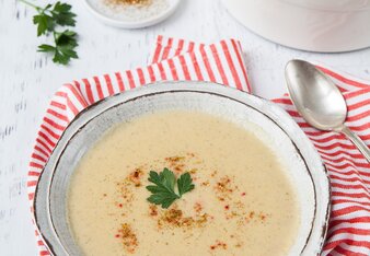 Auf dem Foto ist ein Teller mit Kartoffel Gemüse-Suppe zu sehen. Das Teller steht auf einem rot-weiß kariertem Tuch. | © SONNENTOR