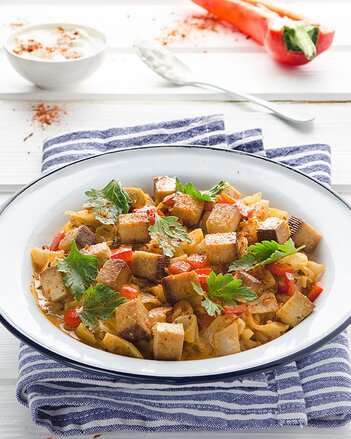 Auf dem Foto ist ein Teller mit Paprika-Rahmkraut mit Tofu zu sehen. Das Teller steht auf einem blau-weißen Tuch. | © SONNENTOR