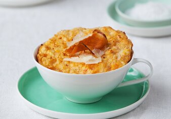 Auf dem Foto sieht man eine Tasse mit einem Süßkartoffelküchlein darin. Das Küchlein ist mit Parmesan und Süßkartoffelchips garniert. | © SONNENTOR