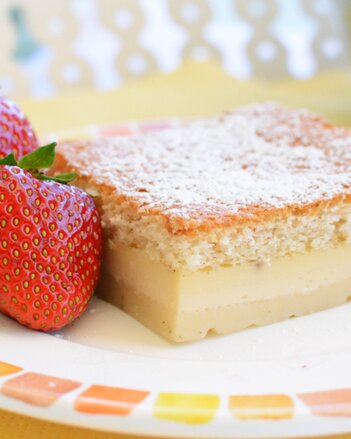 Auf dem Foto ist ein Teller mit Vanille-Schichtkuchen zu sehen. Daneben sind zwei frische Erdbeeren zu sehen. | © SONNENTOR