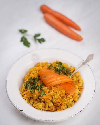 Auf dem Foto ist ein Teller Karotten-Orangen-Porridge zu sehen. Darauf sind hauchdünne Karottenscheiben zu sehen. | © SONNENTOR