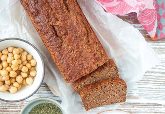 Auf dem Foto ist Gemüse Kraftbrot zu sehen. Daneben sind zwei Schüsselchen mit Kichererbsen und Gewürzen zu sehen. | © SONNENTOR