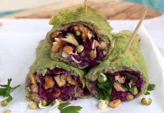 Auf dem Foto sind grüne Wraps gefüllt mit Rotkohl, Walnüssen und Kichererbsen zu sehen. Die Wraps werden mit kleinen Holzspießen zusammen gehalten. | © SONNENTOR