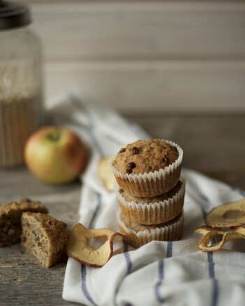 Auf dem Foto sind drei Müslimuffins zu sehen. Daneben liegen Apfelringe und auch frische Äpfel. | © SONNENTOR