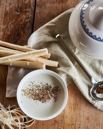 Auf dem Foto ist eine Tasse mit Spargelcreme Suppe zu sehen. Daneben ist frischer Spargel zu sehen. | © SONNENTOR