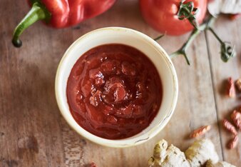 Auf dem Foto sieht man ein Schälchen mit süßer Chili Sauce. Daneben sind Ingwer, Knoblauch, Paprika,  Tomaten und Chili zu sehen. | © SONNENTOR