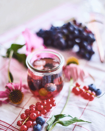 Auf dem Foto ist die Bengelchen Bowle mit Wacholderbeeren zu sehen. Daneben sind Ribiseln, Heidelbeeren und Blüten zu sehen. | © SONNENTOR