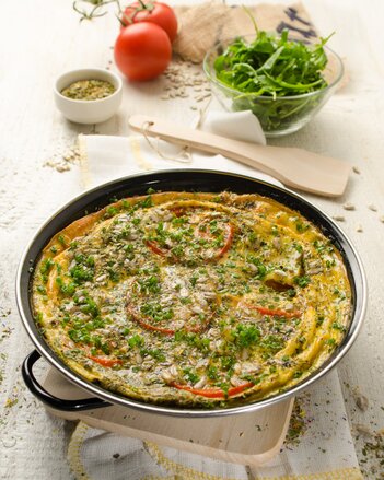 Auf dem Foto ist eine große Pfanne mit Frühlingsomelett zu sehen. Neben der Pfanne sind Rucola, Tomaten und Gewürze zu sehen. | © SONNENTOR