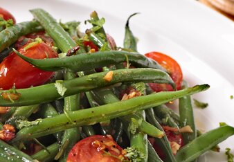 Auf dem Foto ist ein Fisolensalat mit Tomaten zu sehen. Dahinter sieht man noch einen zweiten Teller mit Fisolen-Tomaten Salat. | © SONNENTOR