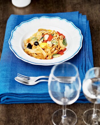 Auf dem Foto ist ein Teller Tagliatelle mit Tofu auf einem blauen Tuch zu sehen. Daneben stehen zwei Gläser. | © SONNENTOR