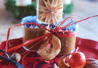 Auf dem Foto sind drei Gläser mit Lebkuchenmarmelade zu sehen. Sie sind mit getrockneten Apfelringen, Holzsternen und Bändern dekoriert. | © SONNENTOR