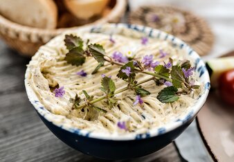 Die Kräuterbutter ist in einem Schüsserl, dekoriert mit essbaren Blüten.  | © SONNENTOR