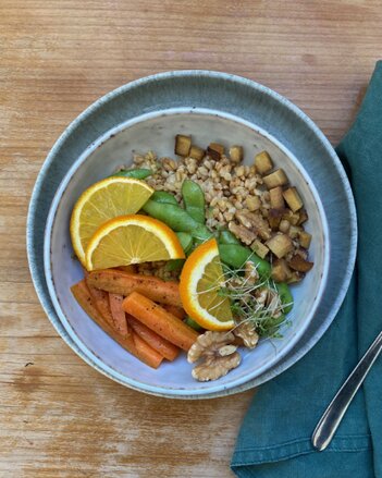 Auf dem Foto ist eine Schüssel mit Einkornreissalat, Edamame und Oregano auf einem Holztisch zu sehen. | © SONNENTOR