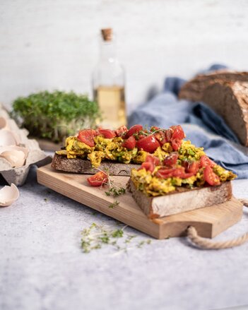 Auf dem Foto sind zwei Scheiben Sauerteigbrot zu sehen. Darauf befindet sich Kurkuma Eierspeise und Tomaten. | © SONNENTOR