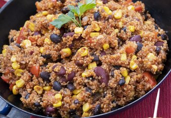 Auf dem Foto sieht man eine Pfanne mit veganem Quinoa Chili. Darauf ist frische Petersilie. Daneben sieht man einen Maiskolben. | © SONNENTOR