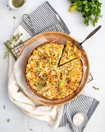 Auf dem Foto ist eine Lauch-Zitronenthymian Ricotta Tarte zu sehen. Daneben sieht man verschiedene Kräuter und Gewürze. | © SONNENTOR