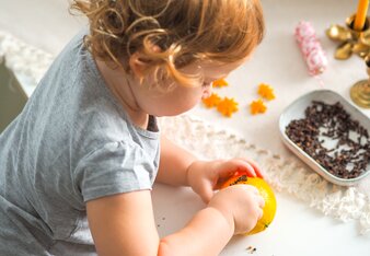 Auf dem Foto ist zu sehen, wie ein Kind Gewürznelken in eine Orange steckt. | © SONNENTOR