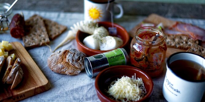 Auf dem Foto sieht man einen Tisch gedeckt mit pikanten Köstlichkeiten wie Brot, Kren, Schafskäse und vielem mehr. | © SONNENTOR